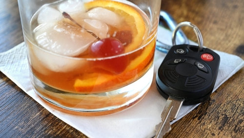 Drink and Drive, drunk driver concept - mixed drink liquor cocktail with key for vehicle at bar